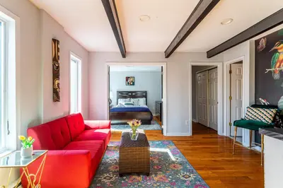 a living room with a red couch and a bed at Twin Pines Retreat Hot Tub Theater Room Fire in East Stroudsburg