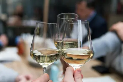 two people holding up glasses of white wine at The Rhyland in Flushing