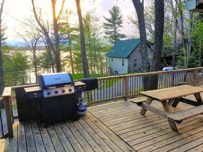 a grill and picnic table on a wooden deck at Lakefront Cabin Rental with Incredible Sunsets on Lake Wallenpaupack, Pennsylvania in Hawley