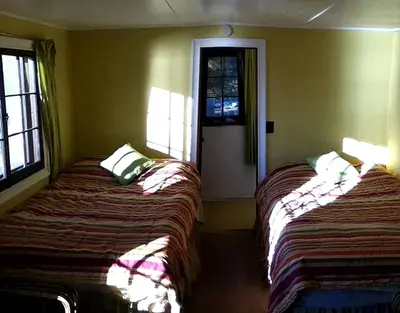 two beds in a room with two windows at Comfortable Cabin Right on Great Sacandaga Lake in Northville, New York in Northville