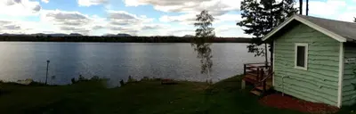 a building next to a lake with a house at Comfortable Cabin Right on Great Sacandaga Lake in Northville, New York in Northville