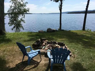two chairs and a fire pit next to a lake at Cozy Cabin with Lovely Views of Great Sacandaga Lake in Northville, New York in Northville
