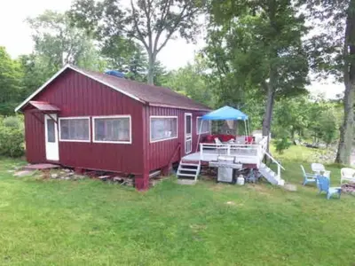 a red house with a picnic table in the yard at Cozy Cabin with Lovely Views of Great Sacandaga Lake in Northville, New York in Northville