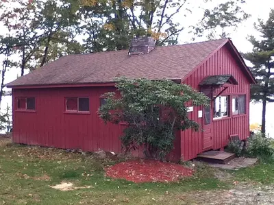 a red house with a tree in front of it at Cozy Cabin with Lovely Views of Great Sacandaga Lake in Northville, New York in Northville