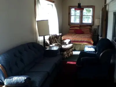 a living room with a couch and a bed at Rustic Cabin Beside the Great Sacandaga Lake in Northville, New York in Northville