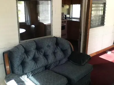 a couch sitting in a living room with a kitchen at Rustic Cabin Beside the Great Sacandaga Lake in Northville, New York in Northville