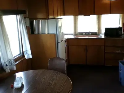 a kitchen with a table and a kitchen with a refrigerator at Rustic Cabin Beside the Great Sacandaga Lake in Northville, New York in Northville