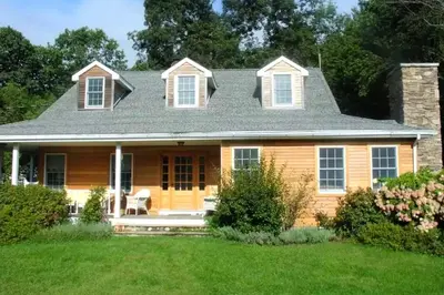 a wooden house with a porch with a lawn at Secluded Cottage Rental with a Heated Pool in Red Hook for Family Getaways in New York State in Red Hook