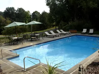 a large swimming pool with chairs and tables and umbrellas at Secluded Cottage Rental with a Heated Pool in Red Hook for Family Getaways in New York State in Red Hook