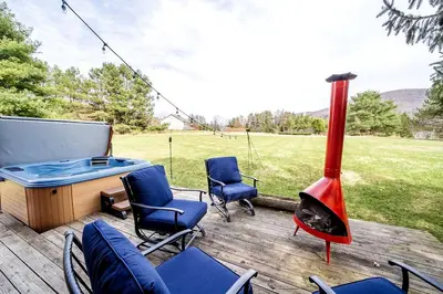 a patio with a fireplace and chairs and a fire pit at Rustic Cabin Rental with a Hot Tub near Windham, New York in Windham