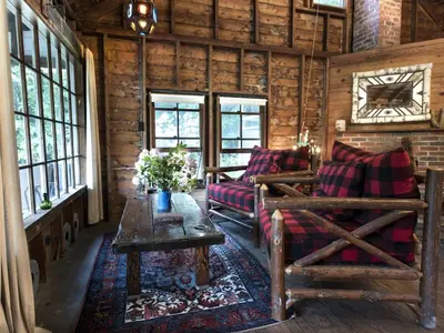 a living room with couches and a table and windows at Secluded and Rustic Cabin Rental with Modern Amenities near Woodstock, New York in Willow