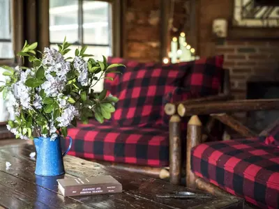a blue vase with flowers on a table in a living room at Secluded and Rustic Cabin Rental with Modern Amenities near Woodstock, New York in Willow