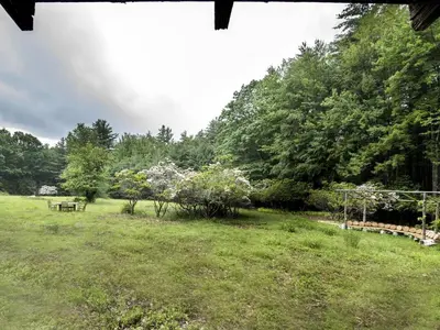 a field with a picnic table and trees in the background at Secluded and Rustic Cabin Rental with Modern Amenities near Woodstock, New York in Willow