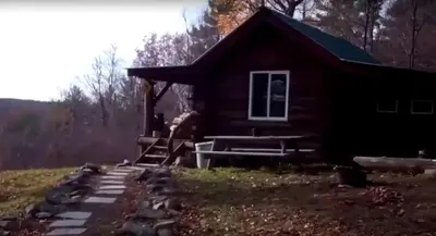a log cabin with a porch and stairs to it at Pet-Friendly Rustic Cabin on Grafton Mountain, New York in Johnsonville