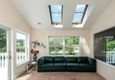 a living room with a green couch and windows at 27-Person Luxury Villa Rental in Hudson Valley, New York in Monroe