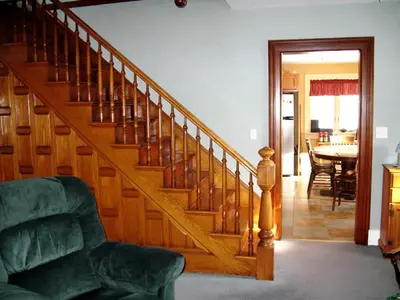 a wooden staircase in a living room with a table at Hilltop Cottage Rental Overlooking Creek near Albany in Upstate New York in Fly Creek
