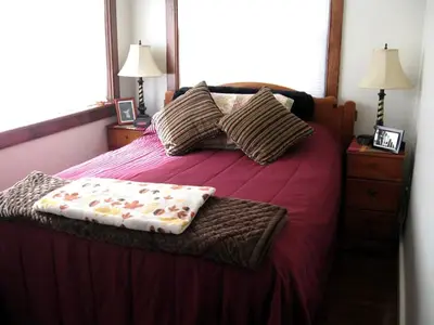 a bedroom with a large bed with red sheets and pillows at Unique Renovated Barn Rental with Pond near Cooperstown, New York in Fly Creek