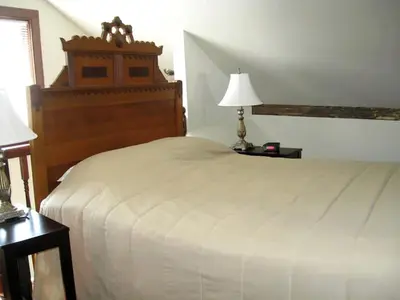 a bedroom with a large white bed and two lamps at Unique Renovated Barn Rental with Pond near Cooperstown, New York in Fly Creek