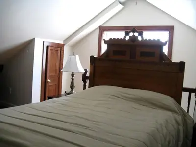 a bedroom with a large bed and a window at Unique Renovated Barn Rental with Pond near Cooperstown, New York in Fly Creek