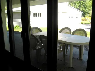 a table and chairs on a porch with a table and a table and chairs at Unique Renovated Barn Rental with Pond near Cooperstown, New York in Fly Creek