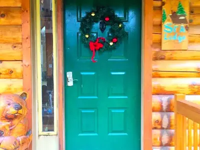 a green door with a christmas wreath on it at Spacious Log Cabin for a Family Getaway near the Zoar Outdoor Adventure Resort in Massachusetts in Charlemont