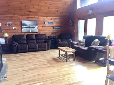 a living room with leather couches and a table at Spacious Log Cabin for a Family Getaway near the Zoar Outdoor Adventure Resort in Massachusetts in Charlemont