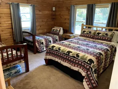 a bedroom with two beds in a log cabin at Spacious Log Cabin for a Family Getaway near the Zoar Outdoor Adventure Resort in Massachusetts in Charlemont