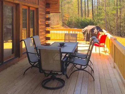 a table and chairs on the deck of a cabin at Spacious Log Cabin for a Family Getaway near the Zoar Outdoor Adventure Resort in Massachusetts in Charlemont