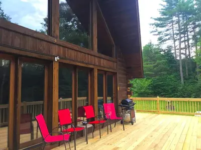 a group of red chairs sitting on a deck at Spacious Log Cabin for a Family Getaway near the Zoar Outdoor Adventure Resort in Massachusetts in Charlemont