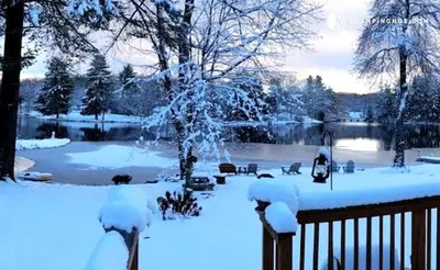 a snow covered yard with a pond and a fence at Charming Waterfront Cottage Rental near Topsmead State Forest, Connecticut in Harwinton