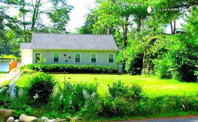 a small white house with a green yard at Charming Waterfront Cottage Rental near Topsmead State Forest, Connecticut in Harwinton