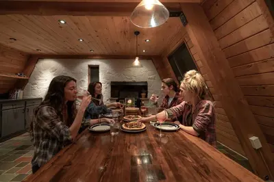 a group of people sitting around a wooden table at Stunning A-Frame Cabin Rental in the Catskills near Albany, New York in Kingston