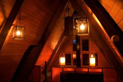 an attic room with lights hanging from the ceiling at Stunning A-Frame Cabin Rental in the Catskills near Albany, New York in Kingston