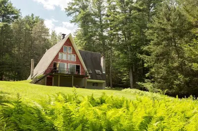 a red house on top of a hill with trees at Stunning A-Frame Cabin Rental in the Catskills near Albany, New York in Kingston