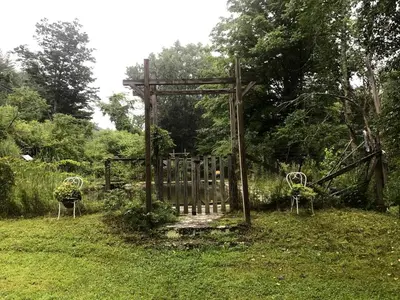 a wooden gate in a field with two chairs at Superb Family Cabin with Mountain Views and Deck in Shandaken, New York in Shandaken