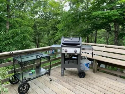 a grill and a cart on a deck at Luxurious Riverfront Cottage with a Hot Tub and a Fireplace near the Twin Lakes, Connecticut in Canaan