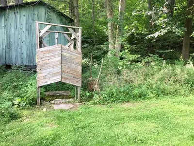 an old wooden chair sitting in the grass at Romantic Mountain Cabin with Stunning Views in Ulster County, New York in Shandaken