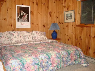 a bedroom with a bed and a lamp and wooden walls at Family-Friendly Cabin in the Deerfield Valley of Mount Snow, West Dover Vermont in West Dover