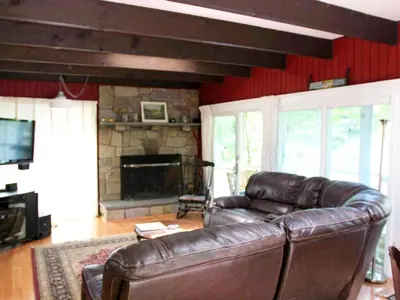 a living room with a leather couch and a fireplace at Delightful Vacation Rental with a Private Dock on Candlewood Lake in Connecticut in New Milford