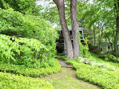 a house in the middle of a yard with trees at Delightful Vacation Rental with a Private Dock on Candlewood Lake in Connecticut in New Milford