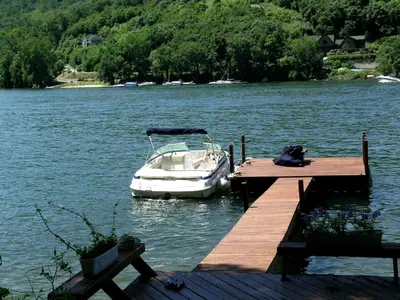 a boat is docked at a dock on a lake at Delightful Vacation Rental with a Private Dock on Candlewood Lake in Connecticut in New Milford