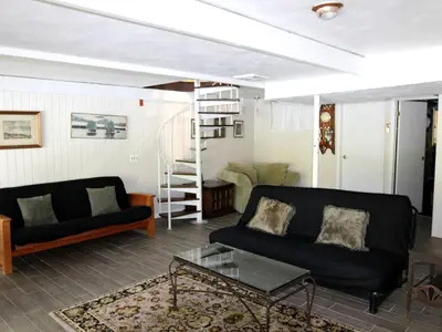 a living room with a black couch and a table at Delightful Vacation Rental with a Private Dock on Candlewood Lake in Connecticut in New Milford