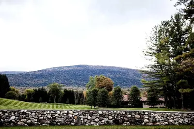 a stone wall in front of a field and a mountain at Gorgeous Green Mountains Vacation Rental with a Pool in Manchester, Vermont in Manchester Center