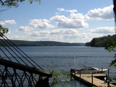 a dock with a boat on a large body of water at Idyllic Waterfront Log Cabin in Wayne County Overlooking Lake Wallenpaupack, Pennsylvania in Lakeville