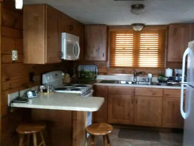 a kitchen with wooden cabinets and a sink and a counter at Idyllic Waterfront Log Cabin in Wayne County Overlooking Lake Wallenpaupack, Pennsylvania in Lakeville