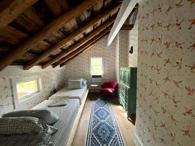 a bedroom with two beds and a red chair at Modern Cottage Perfect for Glamping in New York State in Accord