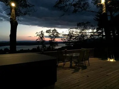 a table and chairs on a deck with a sunset at Fabulous New York Cottage Rental near Ashokan Reservoir in Glenford