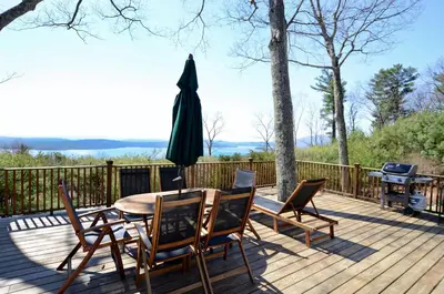 a wooden deck with a table and chairs and an umbrella at Fabulous New York Cottage Rental near Ashokan Reservoir in Glenford