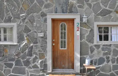 a stone house with a wooden door and two windows at Idyllic Getaway Cottage in the Woods near Woodstock, New York in Woodstock