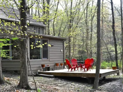 four red chairs and a table on the porch of a cabin at Idyllic Getaway Cottage in the Woods near Woodstock, New York in Woodstock